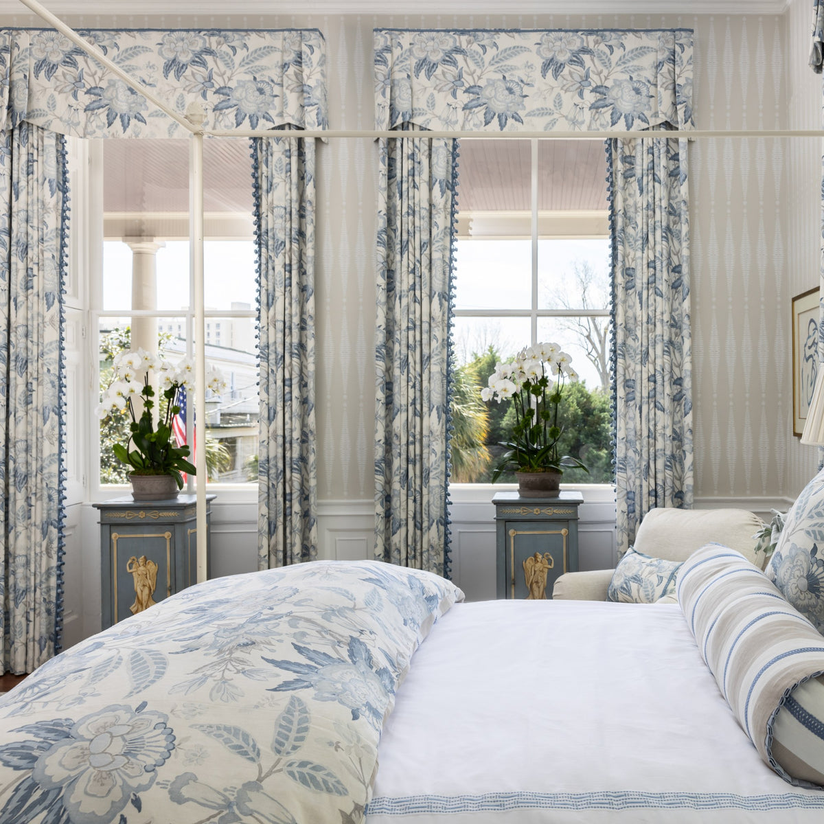 Custom floral drapery panels and valances framing two bedroom windows in a Charleston home